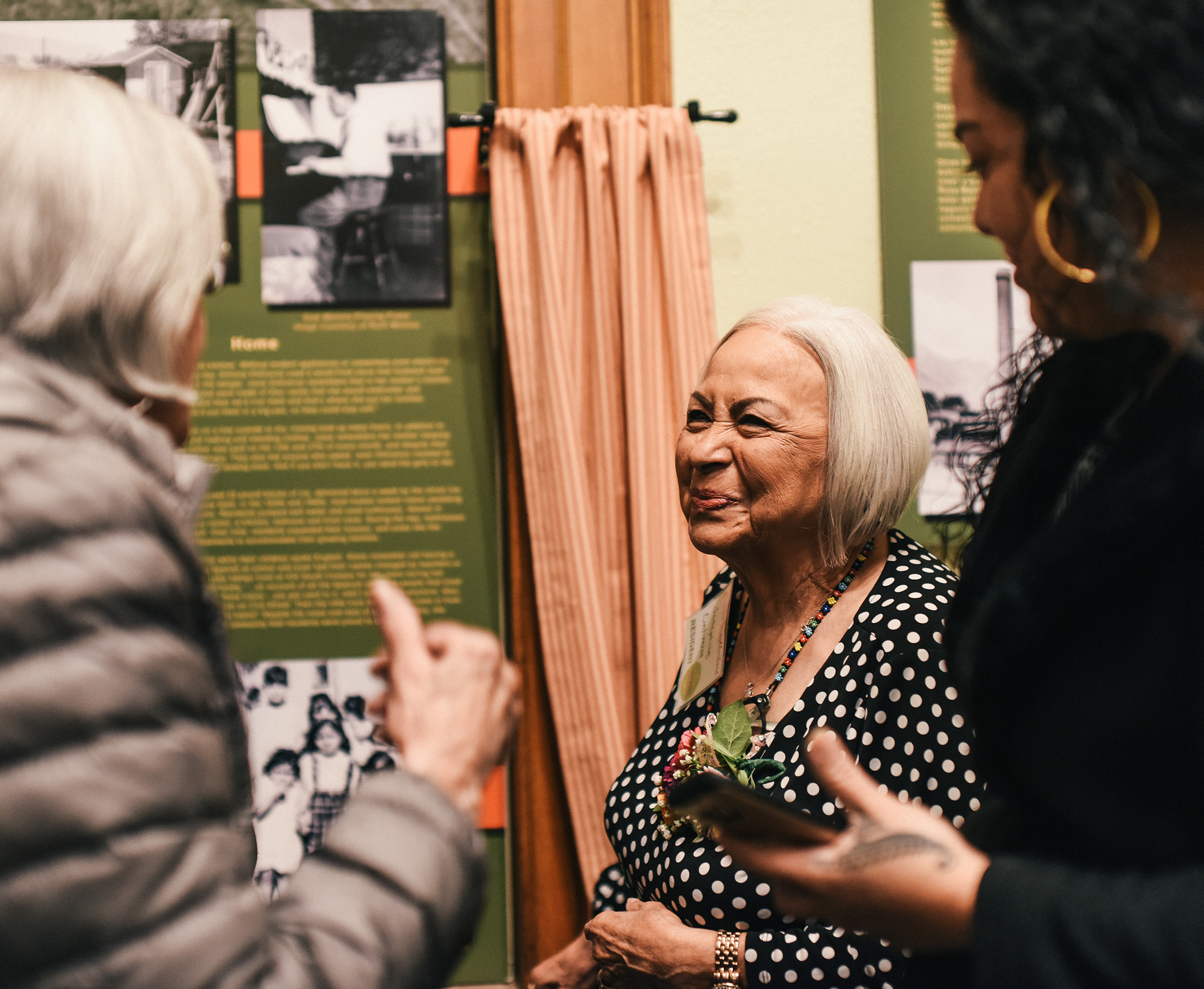 Three women are talking in the Conejos exhibit at the Colorado Springs Pioneers Museum