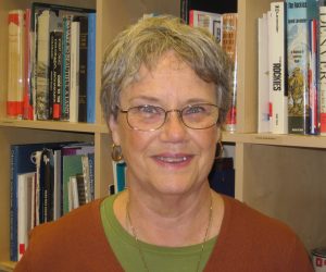 Thomiana (Tommi) Davis stands in front of a bookshelf