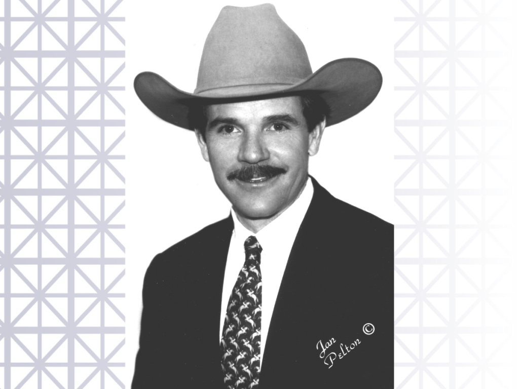 A black and white photo of Kirk Hanna, a mustachioed man wearing a suit and a cowboy hat