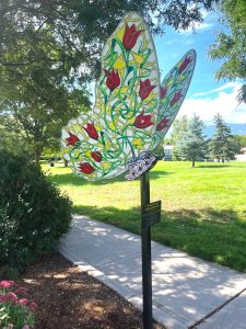 A Public Art Piece of a butterfly with tulips and vines detailed on the wings. The Public Art Piece is in a City of Colorado Springs Park.