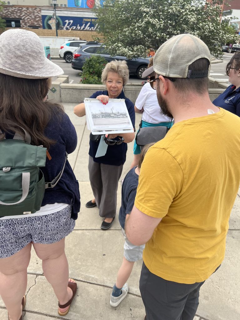 Museum Volunteer showing images to guests while outside on a walking tour.
