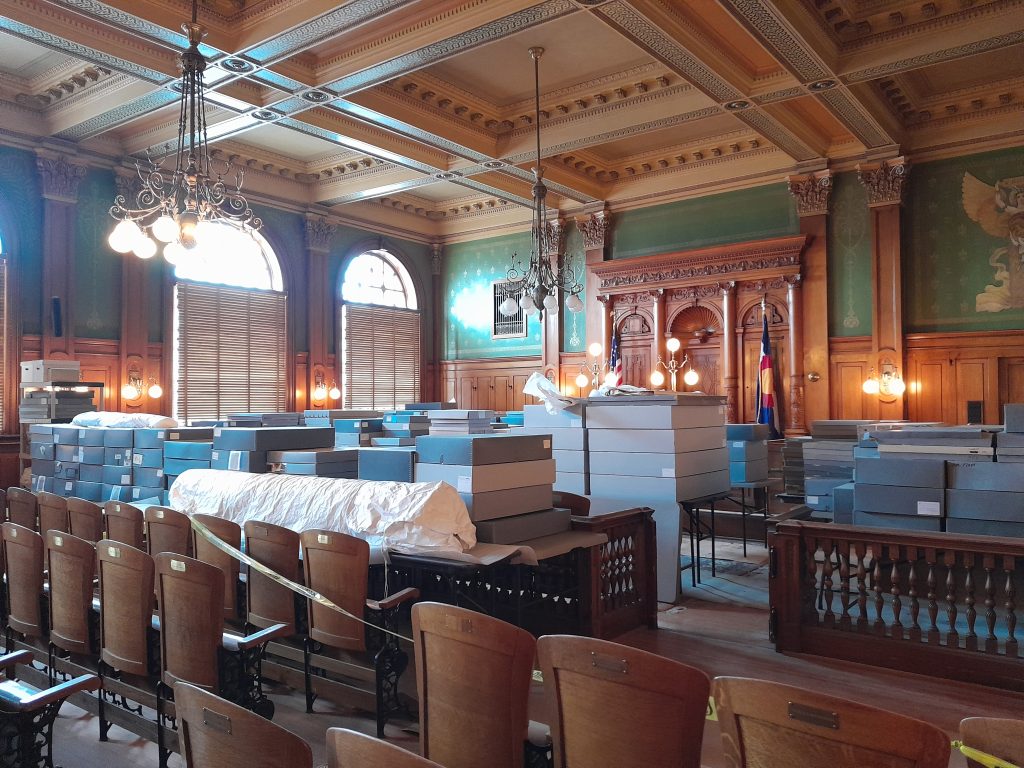 The CSPM's historic courtroom with boxes of textiles sitting on tables.