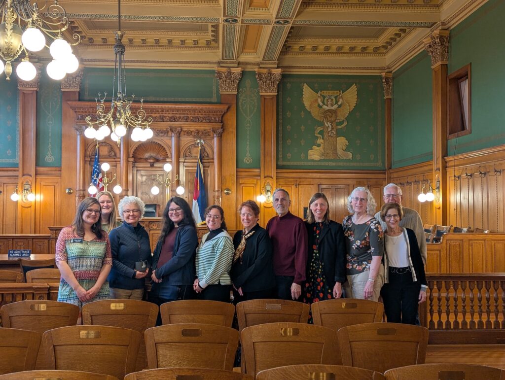 A group of collections volunteers poses for a photo in the museum's Division 1 Courtroom.