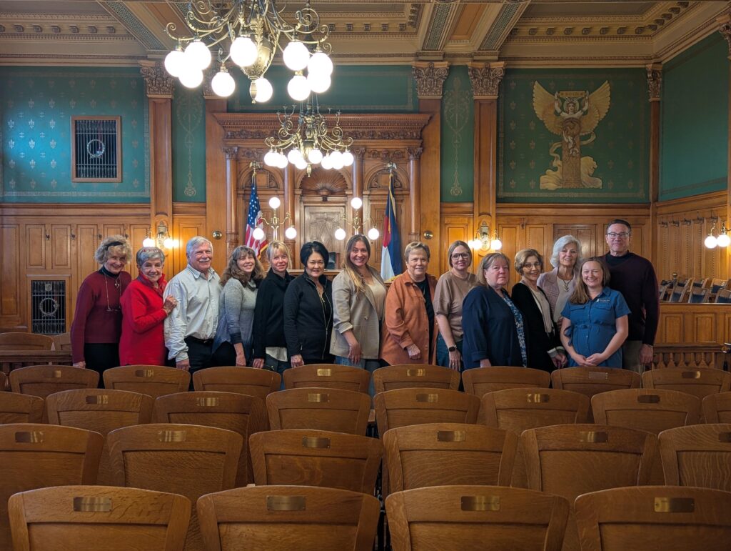 A group of museum committee members poses for a photo in the museum's Division 1 Courtroom.
