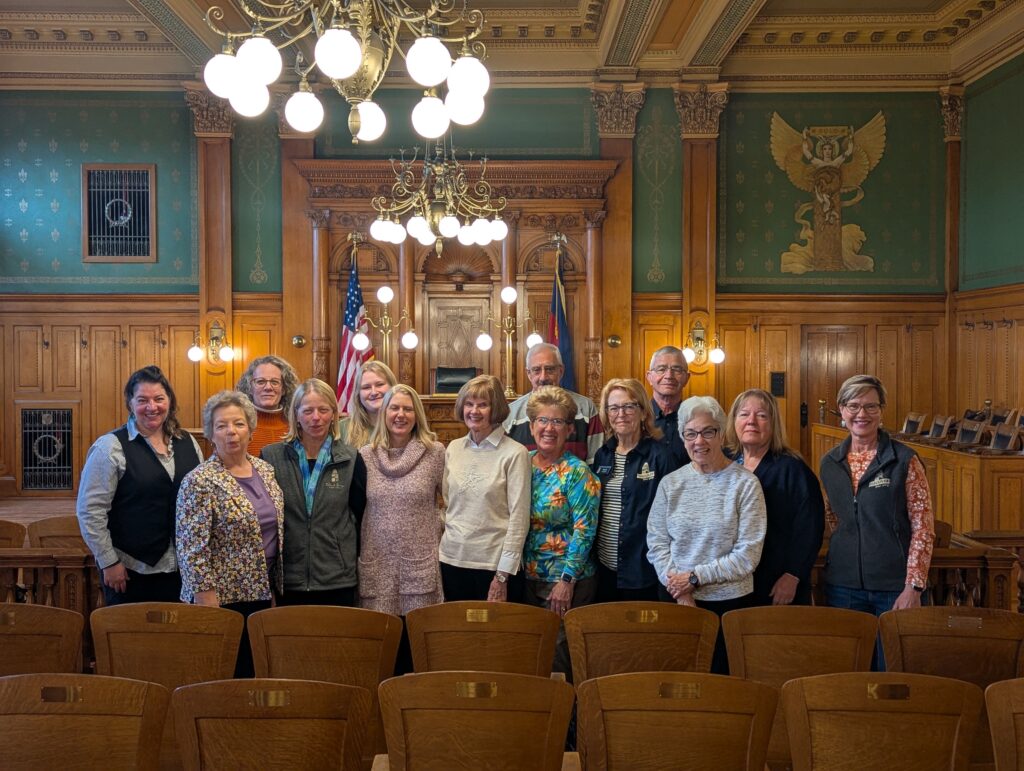 A group of education volunteers poses for a photo in the museum's Division 1 Courtroom.