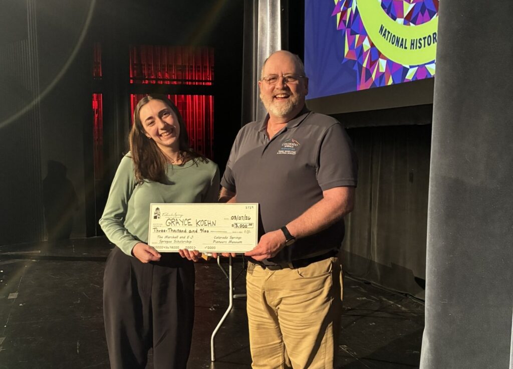 High school student and museum director pose for a photo holding a large check.