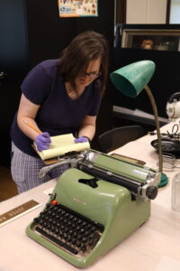 Registrar Caitlin Sharpe taking notes to determine the date of the Olivetti typewriter.