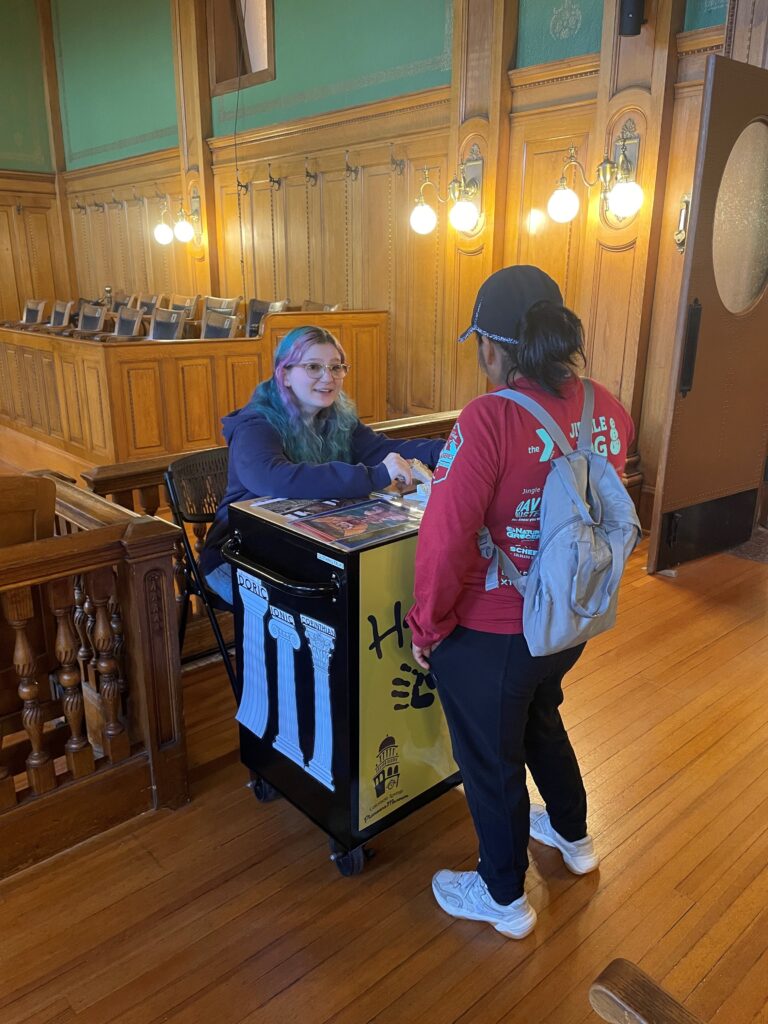 Junior Docent Mentor, Macey Breckon, sharing stories with a guest in the Division I Courtroom.